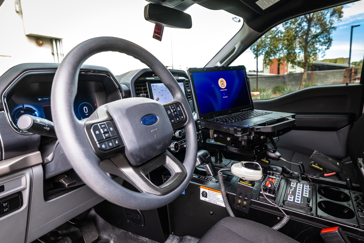 A steering wheel and a laptop can be seen in the frontseat area of a truck.